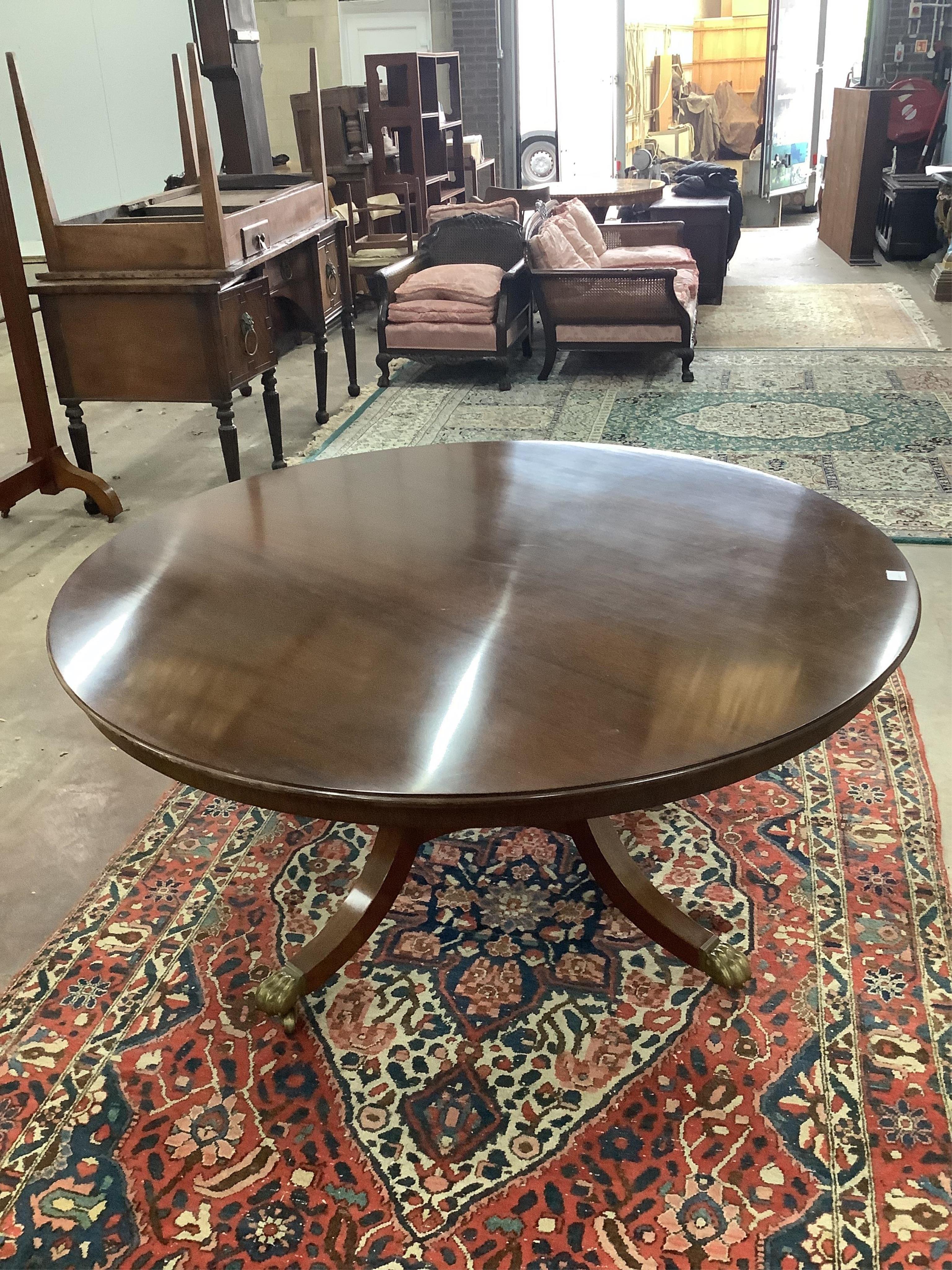 A reproduction George III style mahogany circular segmental extending dining table, diameter 155cm, 230cm extended, height 72cm. Condition - fair